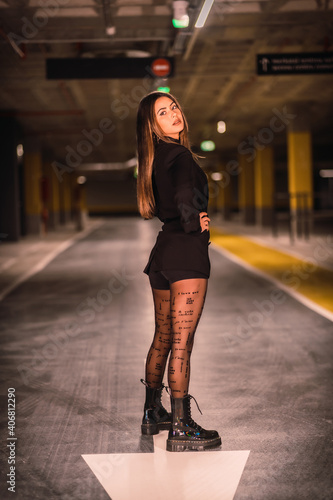 Young Caucasian model perched on the asphalt of an empty underground car park. Night urban session in the city