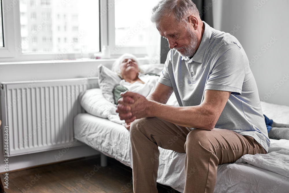sick senior woman with her caring elderly husband sitting close to her, support and help, man sits with head down. medicine concept sick senior woman with her caring elderly husband sitting close to her, support and help, man sits with head down. medicine concept