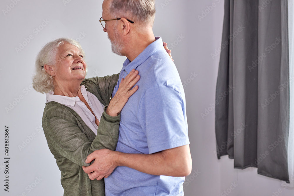 Fototapeta premium senior couple dancing in living room, husband holding hand of mature wife enjoying fun together, spend holidays, leisure retirement ifestyle at home. in casual domestic wear