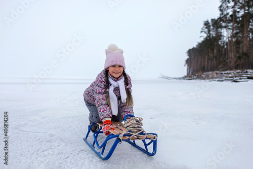 School age girl have fun on the frozen lake and enjoying a sleigh ride. Winter, silence and wild nature, active winter weekend, seasonal outdoor activities, happy family lifestyle, copy space