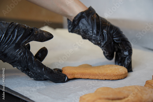 the cook makes cookies with his gloved hands and puts the finished cookies on paper