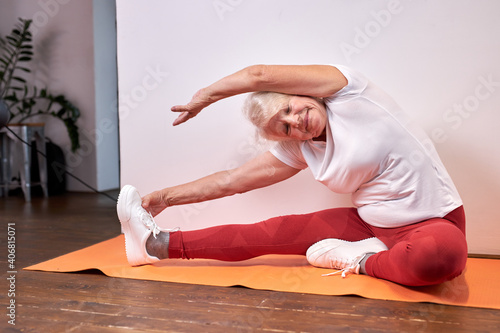 senior woman do sport exercises at home on the floor, beautiful healthy woman stretching arms and legs, enjoy yoga, lead healthy lifestyle