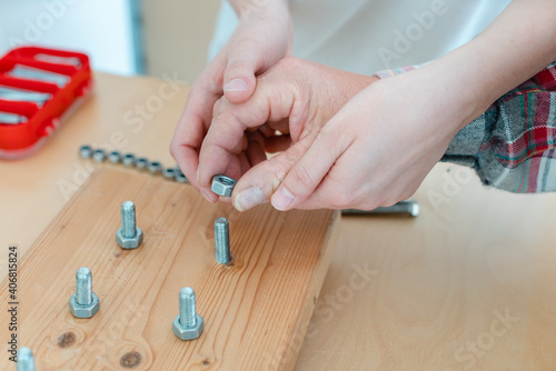 Closeup of man in occupational therapy screwing nut on bolt