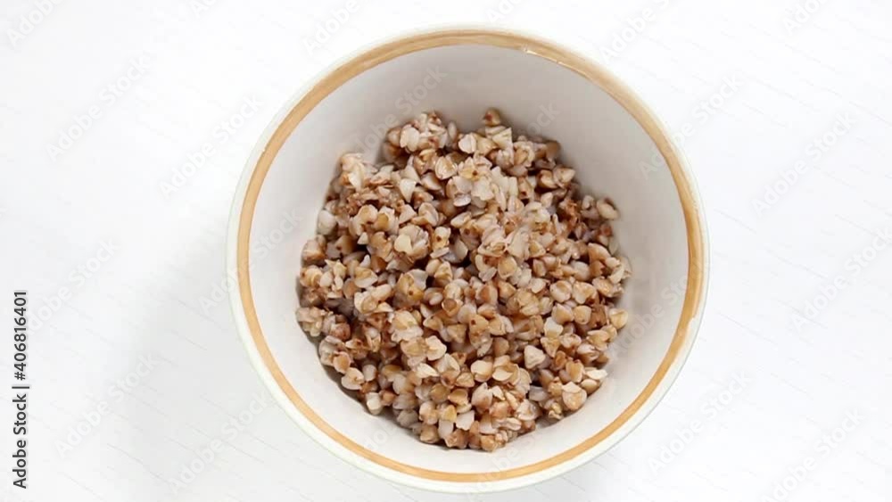 Boiled buckwheat in a plate on a white background. Simple and effective buckwheat diet. The view from the top. Boiled buckwheat in a plate on a white background. Simple and effective buckwheat diet. The view from the top.