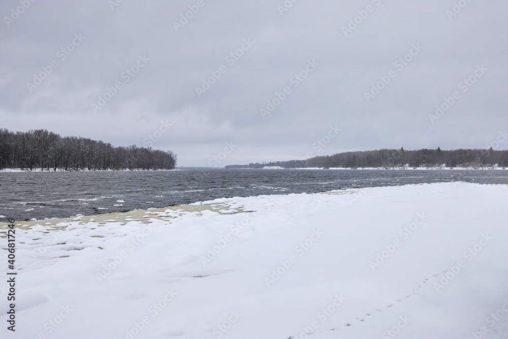 Looking down partially frozen Ottawa River with ice and snow, whitecaps on water, dark clouds, nobody