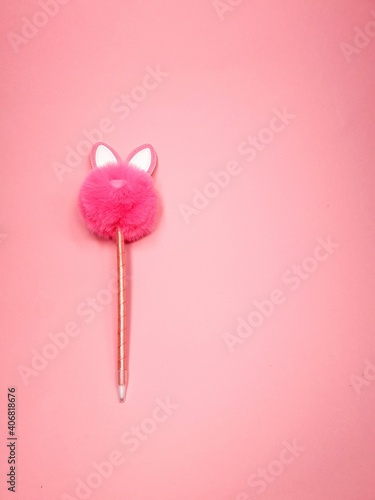 Pink fluffy rabbit in the form of a pompom and a pen on a pink background. Creative rabbit pompom with cute ears. copy space . Easter Bunny rabbit