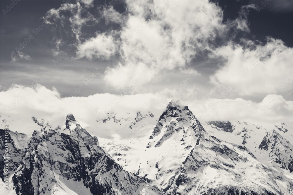 High snowy mountains in clouds at sun winter day High snowy mountains in clouds at sun winter day