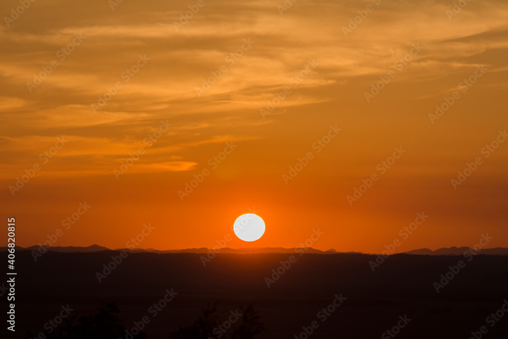 A landscape of the golden sky, the silhouetted earth and the setting sun