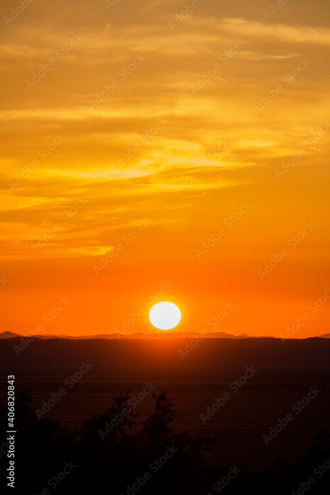 A landscape of the golden sky, the silhouetted earth and the setting sun