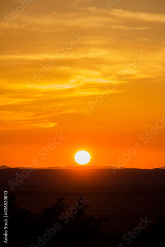 A landscape of the golden sky, the silhouetted earth and the setting sun © Wako