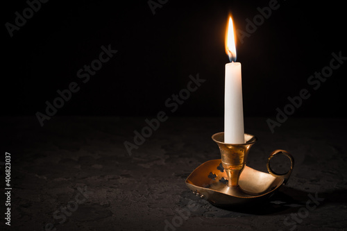 Burning candle  in vintage candlestick on black background