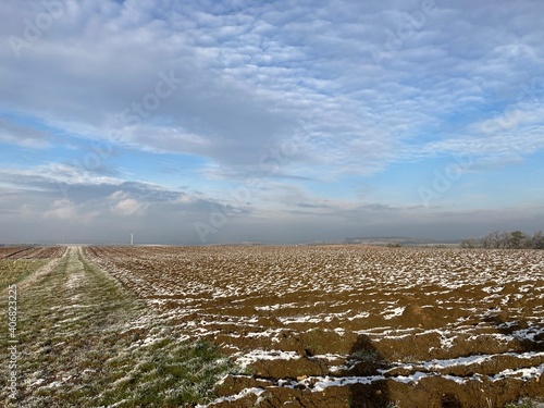 snow melting on a wide field on a sunny winters day with some clouds