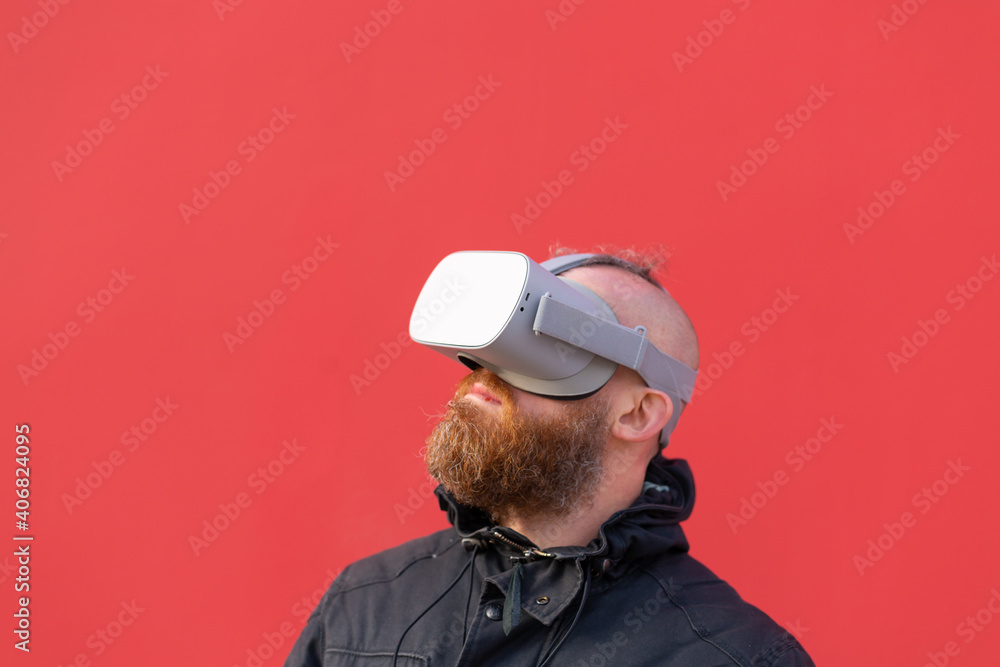 Emotional portrait of a man on the street wearing reality glasses against the background of a red wall Emotional portrait of a man on the street wearing reality glasses against the background of a red wall