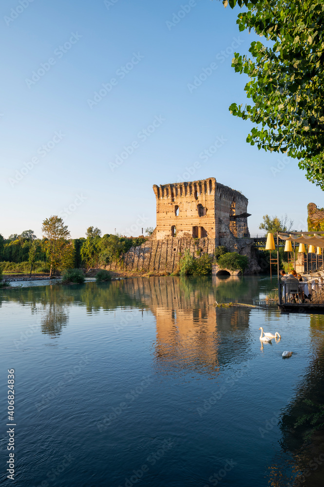The beautiful medieval village of Borghetto di Valeggio sul Mincio. Detail of the river medieval tower with the bridge the swans and the medieval buildings. Verona, Veneto, Italy
