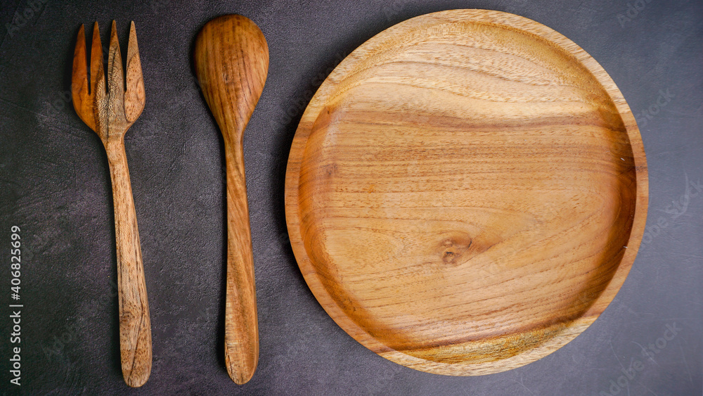 wooden empty plate on a dark stone background, a blank for design. wooden empty plate on a dark stone background, a blank for design.
