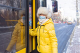 Young smiling woman walks into the bus on a winter day