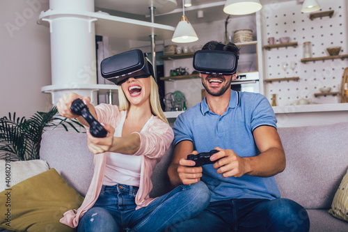 Wall Mural Happy couple playing video games with virtual reality glasses - Young people hav