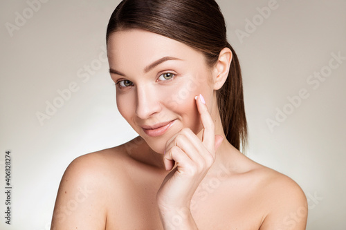Fotografija Beautiful brunette caucasian young woman prepare herself for a make up, applying cream on her face