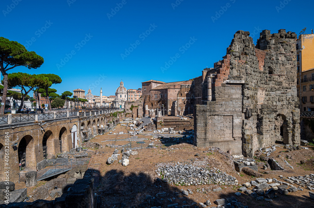 Detail of the Ruins of the Forum of Augustus, the Suburra Via dei Foro Imperiali in a sunny day, blue sky. Capitals, columns in the distance, the churches of Rome, Trajan's markets. Rome