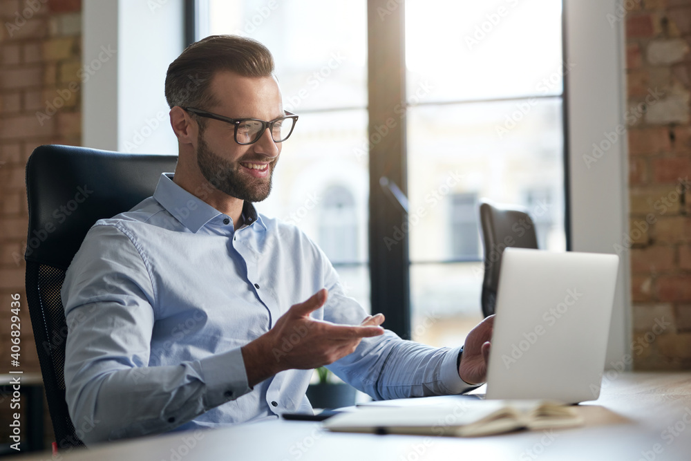 Mirthful employee looking at the laptop screen and smiling Mirthful employee looking at the laptop screen and smiling