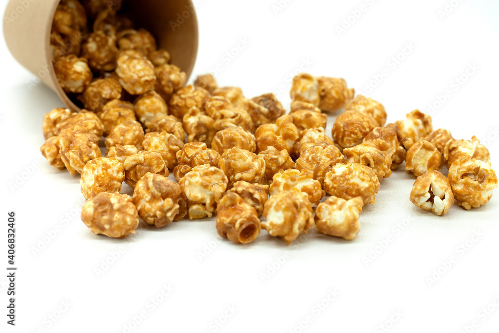 Popcorn with caramel close-up. Popcorn spilled out of a paper cup. White background. Popcorn with caramel close-up. Popcorn spilled out of a paper cup. White background.
