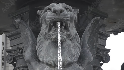 Fountain in the shape of a lion throwing water. Stone fountain in slow motion.