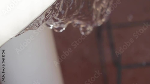 Drops of water falling from a table. Water fall in slow motion from white table