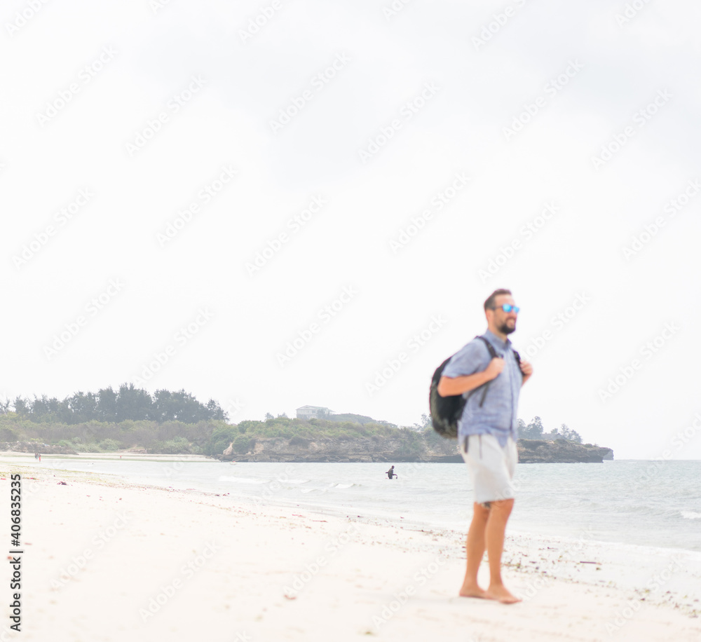 Cheerful adult man with bag having fun on the tropical beach