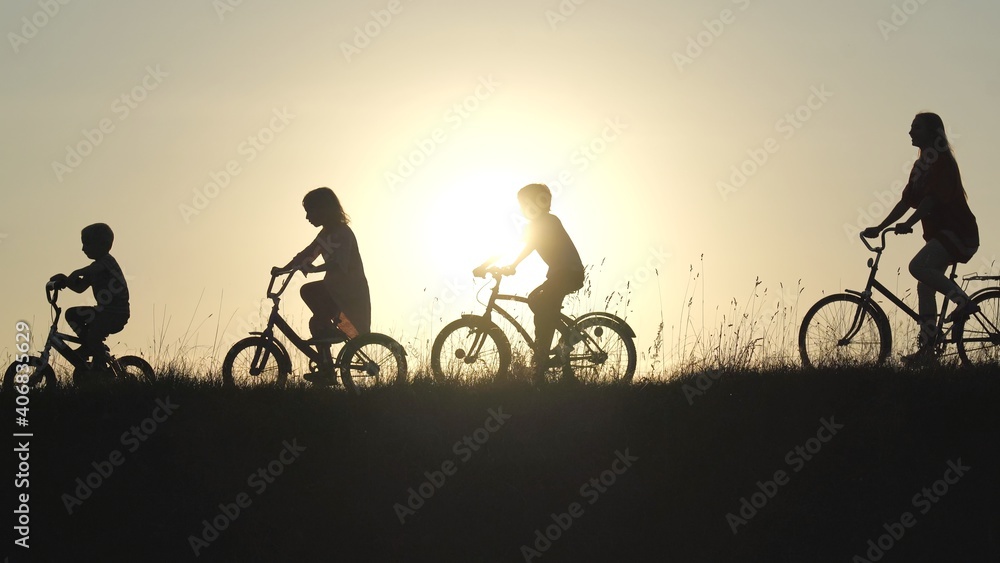 Obraz premium Silhouettes of a large large family on bicycles at sunset.