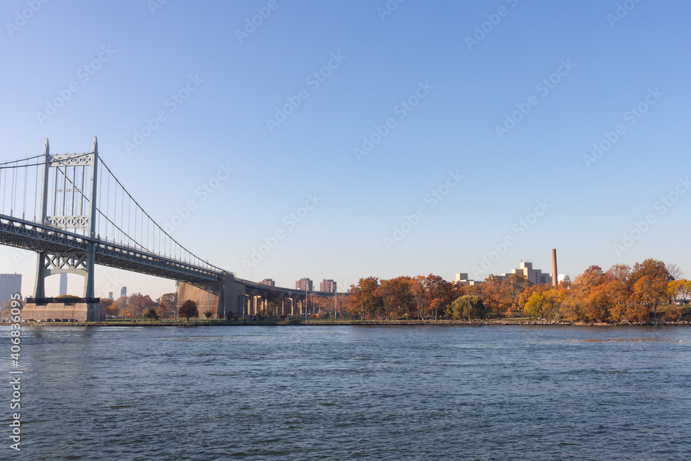 The Triborough Bridge over the East River with the Shore of Randalls and Wards Islands during Autumn with Colorful Trees in New York City