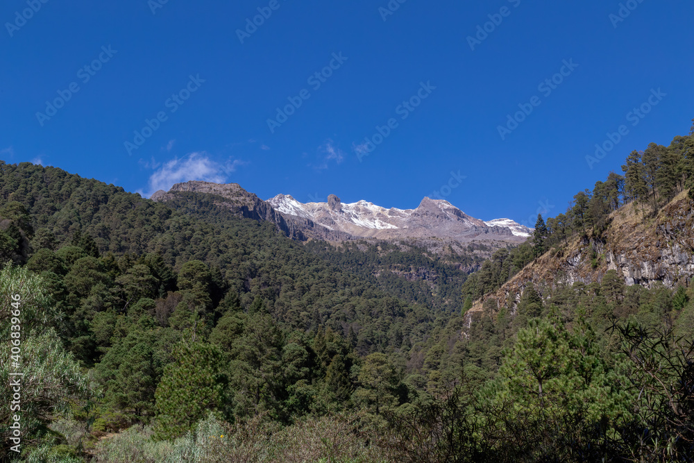 Landscape of the Iztaccihuatl Mountain covered in greenery under a blue sky in Mexico