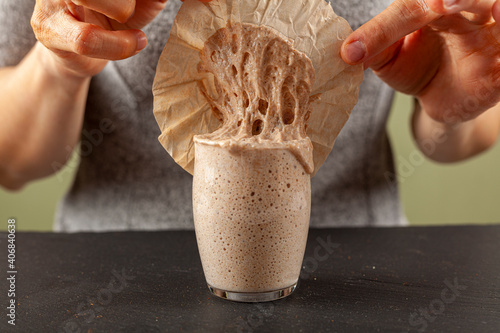Εκτύπωση καμβά A woman is carefully removing the top cover of a sourdough starter culture which is about to overflow the glass cup