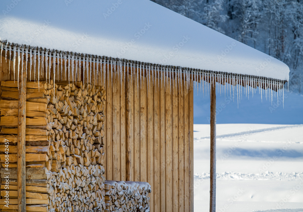Fototapeta premium Wooden huts covered in snow and perfectly lined up icicles
