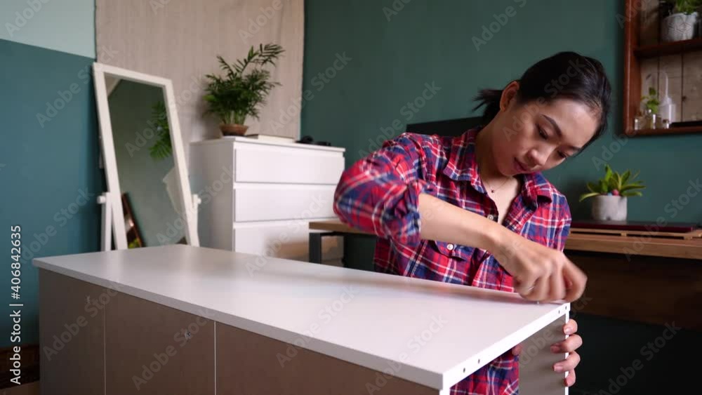 Asian woman assembling furniture alone at home Asian woman assembling furniture alone at home