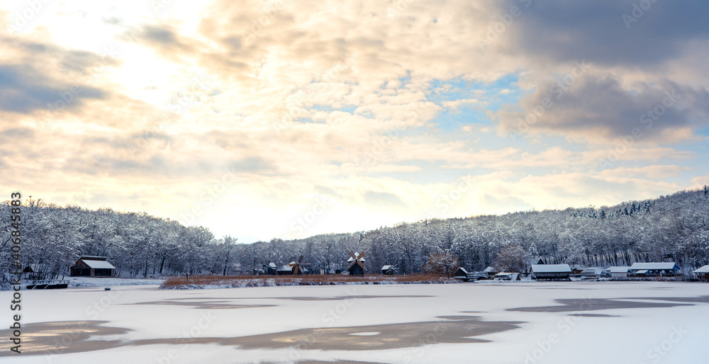 Obraz premium Winter panorama with windmills and frozen lake in a cloudy cold day