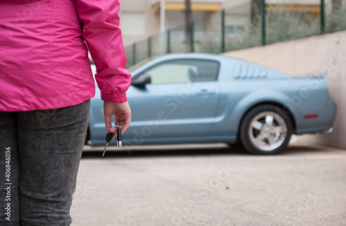 Woman's hand holding modern car keys ready for rental - Concept of transportation with automobile second hand sale and trade