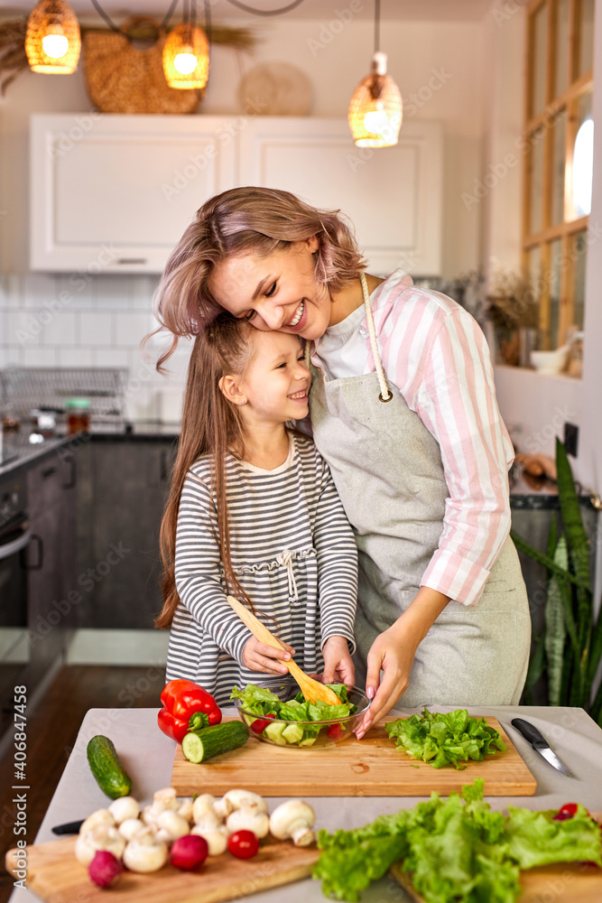 jolly child girl preparing a salad with her mother in the modern light kitchen, enjoy the process of preparing meal jolly child girl preparing a salad with her mother in the modern light kitchen, enjoy the process of preparing meal