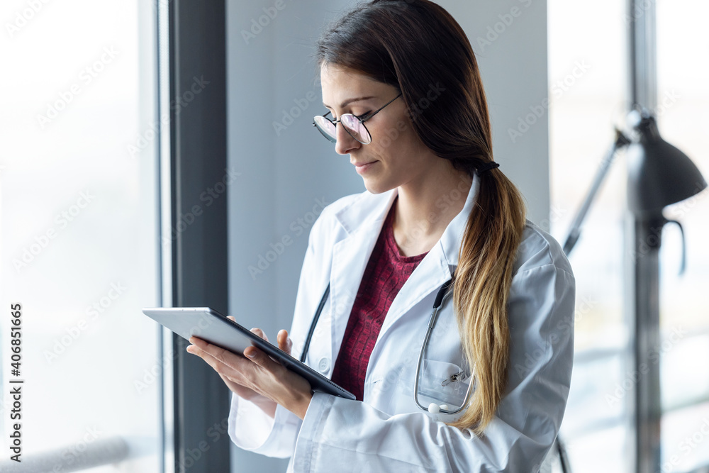 Concentrated young female doctor working with digital tablet in the consultation at hospital. Concentrated young female doctor working with digital tablet in the consultation at hospital.