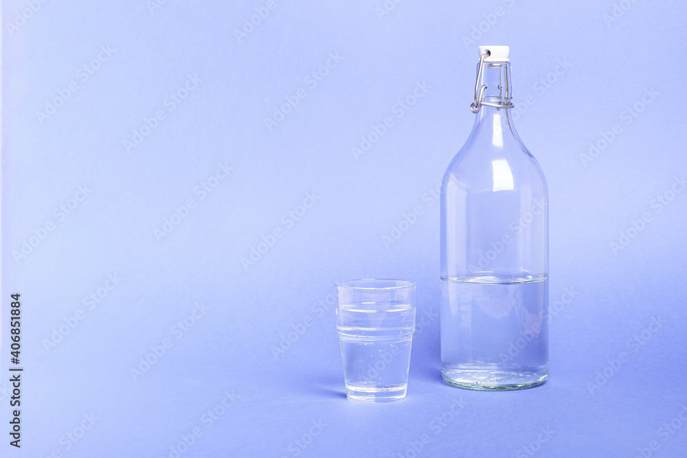 Glass with water near to bottle on blue background Glass with water near to bottle on blue background