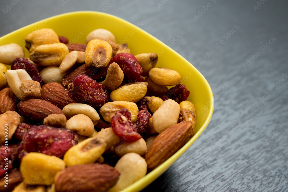 Some peanuts, raisins and nuts in a pot on a dark wooden table Some peanuts, raisins and nuts in a pot on a dark wooden table