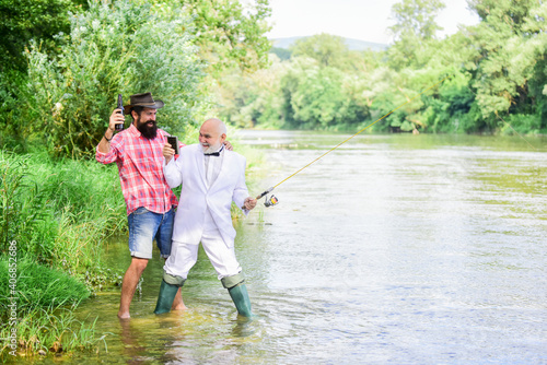 Fun and relax. Weekend time. Bearded man and elegant businessman fishing together. Fishing skills. Set up rod with hook line and sinker. Fishing and drinking beer. Men relaxing nature background