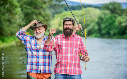Family is our natural resource. two happy fisherman with fishing rods. father and son fishing. summer weekend. mature men fisher. male friendship. family bonding. hobby and sport activity. Trout bait
