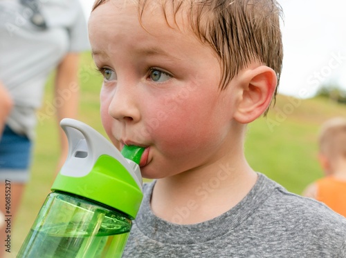 Children drinking water. A thirsty boy taking a water break after playing outdoor.