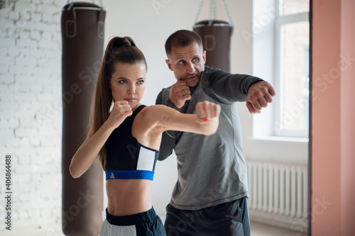 In a spacious loft, a male trainer and his female mentee conduct a boxing training session