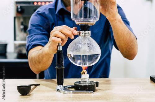 Professional coffee maker - Barista using coffee siphon brewing hot espresso at coffee shop.