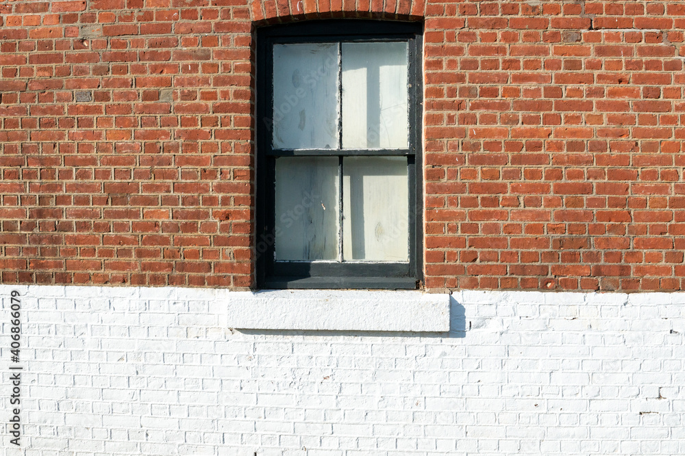 The exterior wall of an old brick building with a double hung wooden ...