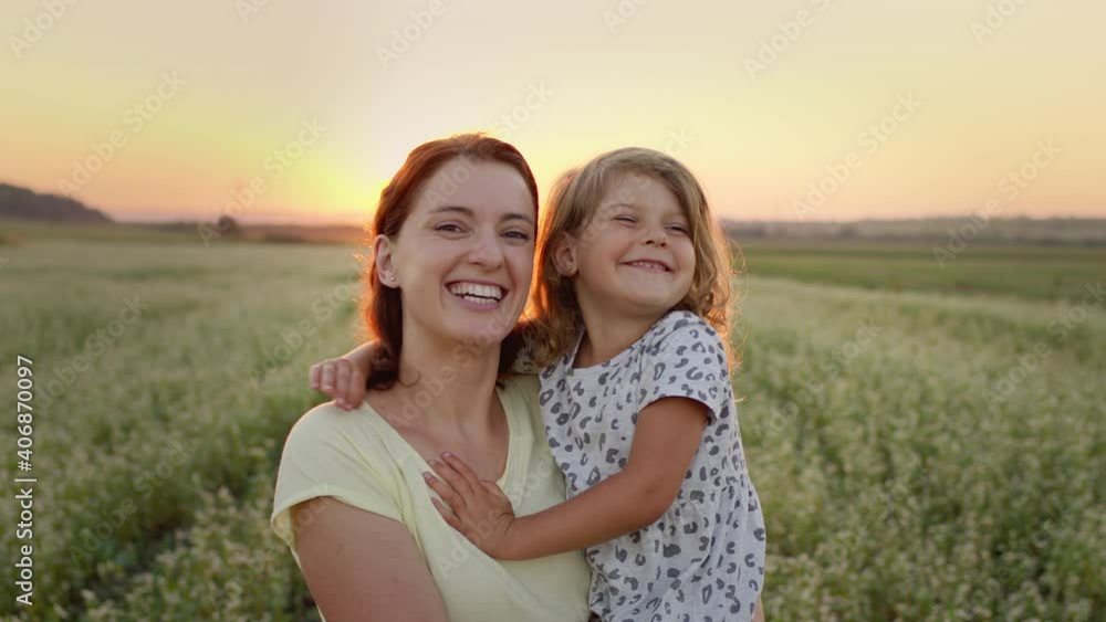 Young Mother Holding Her Daughter In Her Arms. They Are In The Middle Of The Field. They Are Both Smiling. Young Mother Holding Her Daughter In Her Arms. They Are In The Middle Of The Field. They Are Both Smiling.