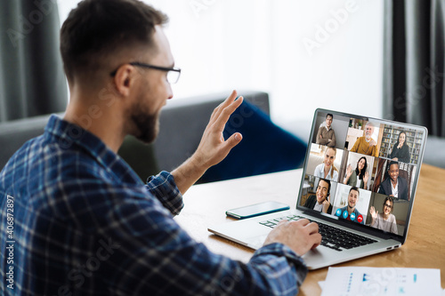 Video call, online business meeting, briefing. Successful caucasian freelancer waving hand and greeting colleagues during video conference. Distant work, online learning photo