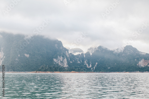 Coastline with cloudy sunset sky, sea and mountains in the Khao Sok National Park, Suratthani Thailand. Nature in twilight period which including of sunrise over the sea. 