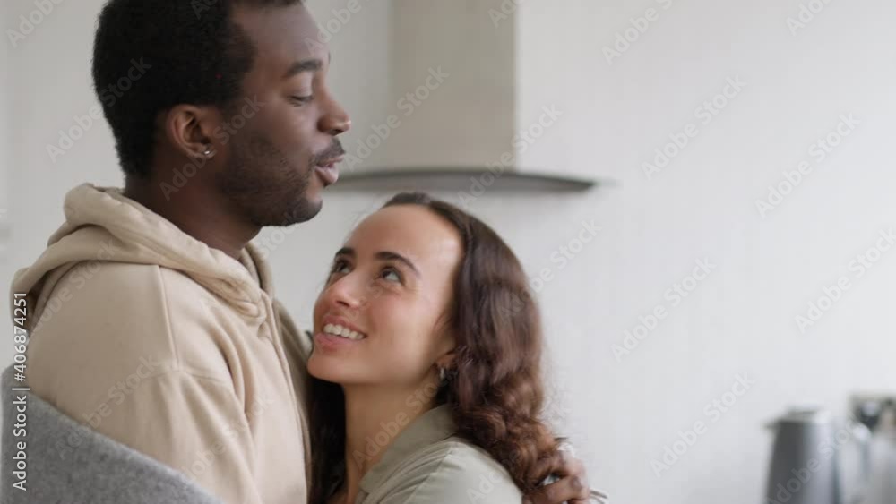 Loving young mixed ethnicity couple cuddling whilst standing in kitchen wrapped in cosy blanket together - shot in slow motion Loving young mixed ethnicity couple cuddling whilst standing in kitchen wrapped in cosy blanket together - shot in slow motion